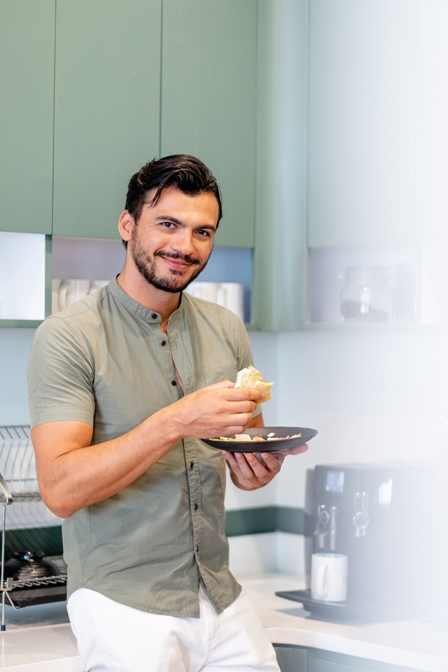 Smiling Man Eating Food in the Office Pantry